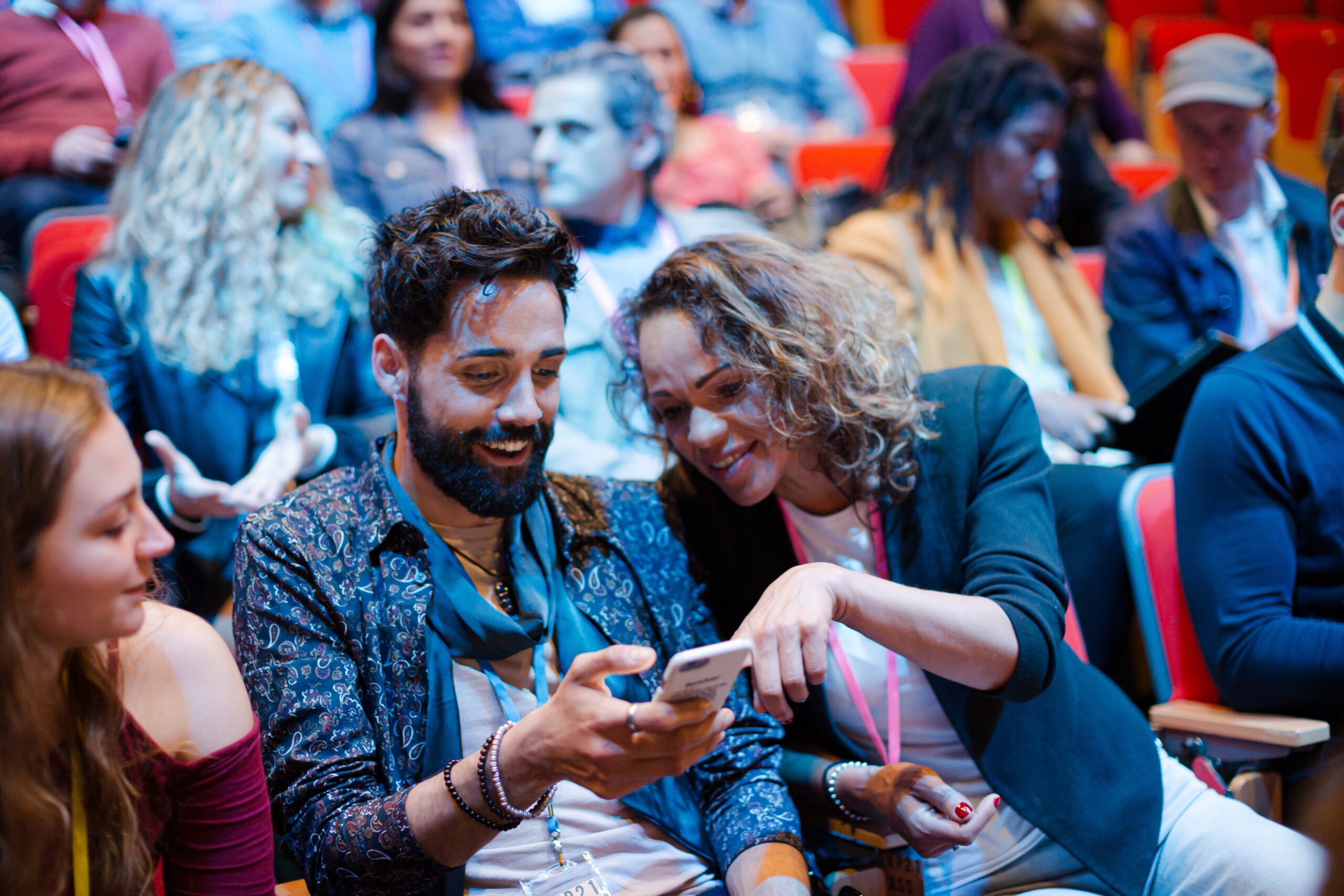 Man and woman with smart phone in conference audience